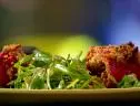 A close up of stuffed piquillo peppers with chorizo and manchego with an arugula salad in between.
