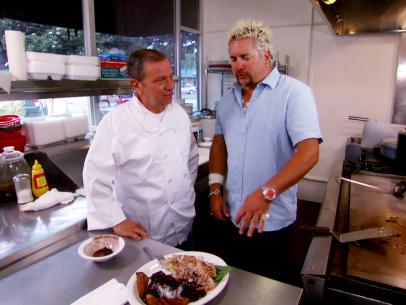Guy Fieri stands with the owner and chef of Mam Bos in Glendale, CA. They are talking about the pork, rice, and beans dinner plate that he just tried.
