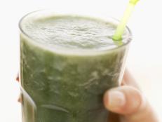 Person holding a glass of thick green vegetable juice
