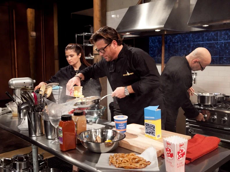 After Hours Chef Scott Conant stealing Chef Alex Guarnaschelli's popcorn for use in his dessert while working on his dessert that must include: popcorn, sour cream, funnel cake and a blue snow cone, as seen on Food Network's Chopped: After Hours.