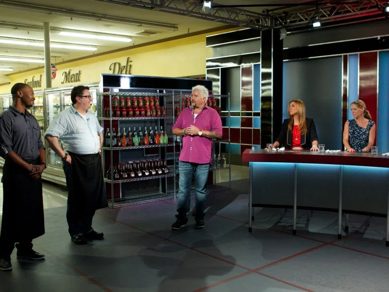 Host Guy Fieri with Chef Stanley Hagerman and Chef Tom Ramsey during the judging of Game 3, Frozen Food Feud, Best Dish, with judges Lorena Garcia, Melissa D'Arabian, and Troy Johnson, as seen on Food Network's Guy's Grocery Games, Season 1.
