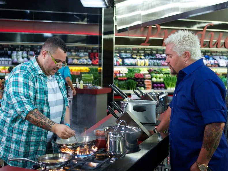 Host Guy Fieri with the chef Nick Wilson, during the cooking part of Game 1, 5 Ingredients Or Less, Asian Stir Fry, 20 minute time limit, as seen on Food Network's Guy's Grocery Games, Season 1.
