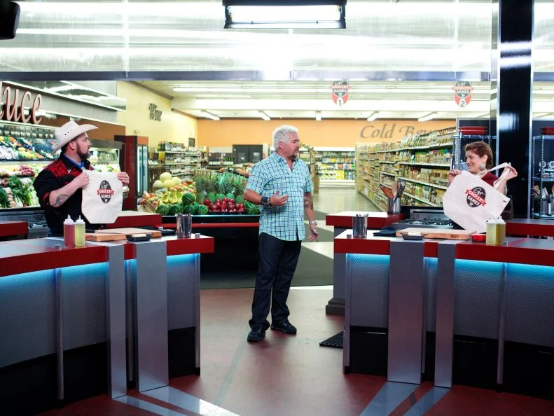 Host Guy Fieri with chef Lenny McNab and chef  Cristina Topham during the introduction of Game 3, Grocery Bag secretly Bag Swap after shopping, Comfort Meal, 3 min to shop and 25 min cooking time, as seen on Food Network's Guy's Grocery Games, Season 1.