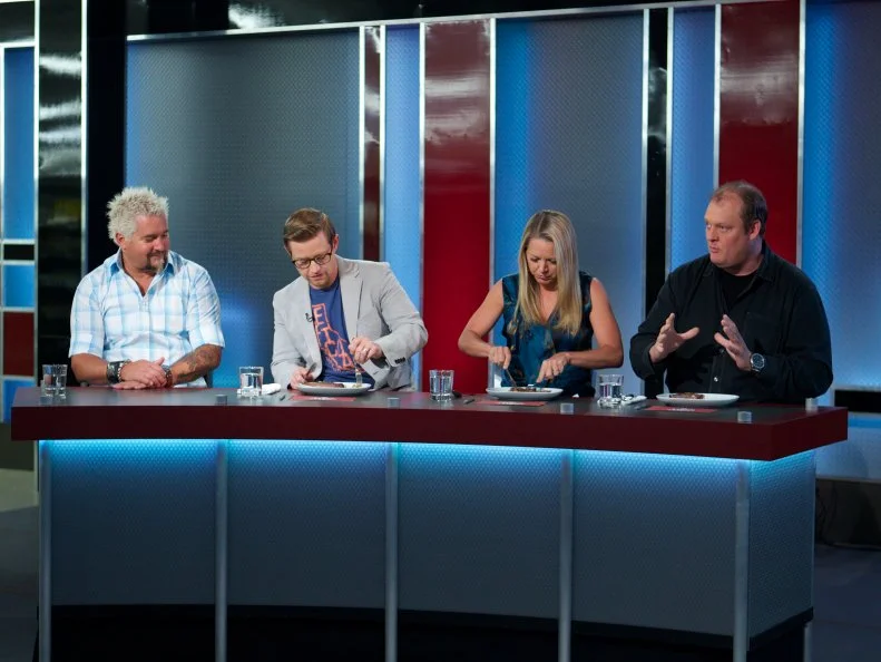 Host Guy Fieri with judges Richard Blais, Melissa D'Arabian, and Beau MacMillan during the judging part of Game 1, Frozen Food Feud, Five Star Dinner, 30 min cooking time, as seen on Food Network's Guy's Grocery Games, Season 1.