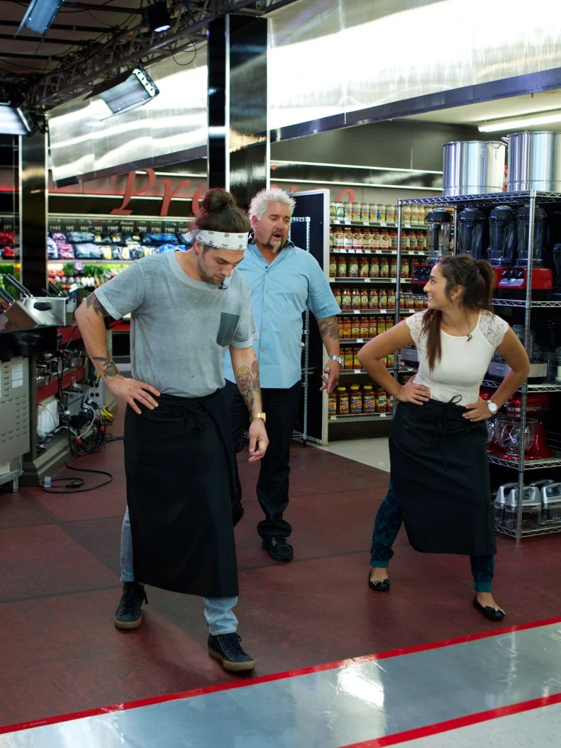 Host Guy Fieri with chefs Samuel Monsour and Cassy Pugh during the start of the shopping part of Game 3, No Carts Allowed, Breakfast, 35 minute time limit, as seen on Food Network's Guy's Grocery Games, Season 1.