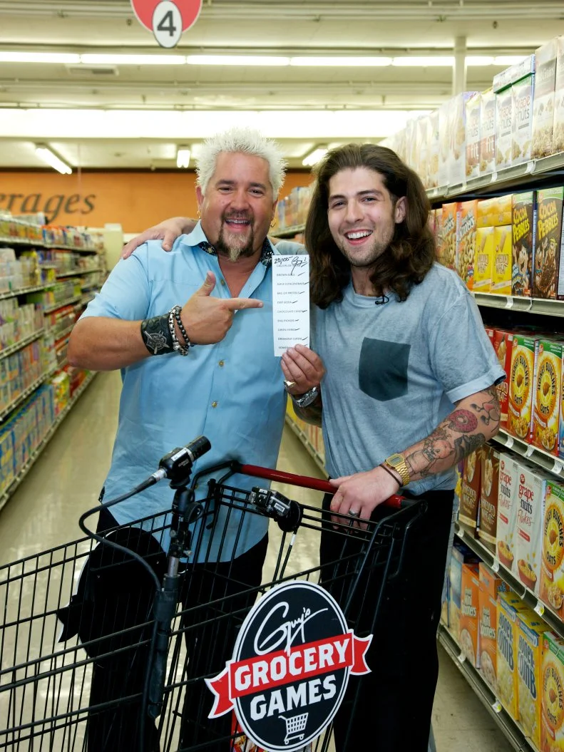 Host Guy Fieri poses with chef Samuel Monsour, winner of Episode 105, Game 3, No Carts Allowed, Breakfast, 35 minute time limit, during the end of the shopping spree with a chance to win $20,000 by grabbing all the items on the grocery list within 2 minutes, as seen on Food Network's Guy's Grocery Games, Season 1. Chef Samuel Monsour wins $20,000.