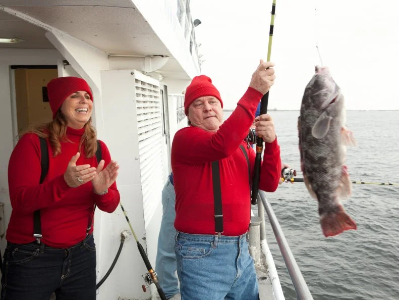 Dr. Bob Schaefer pulls his fish out of the water while Sue Mangogna cheers for him, as seen on Food Network's Worst Cooks in America, Season 4