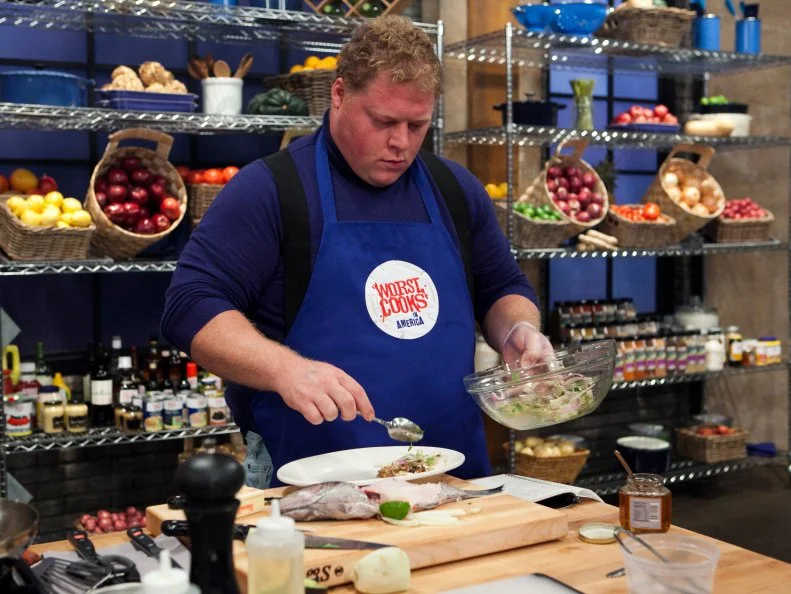 The blue teams Mike (Big Mike) Paul during the fish challenge while attempting to recreate the Chef's Crispy skin black sea bass with avacado, tomatillo and  fennel relish , as seen on Food Network's Worst Cooks in America, Season 4
