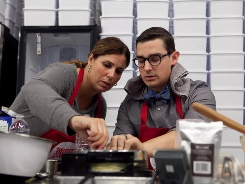 Sue Mangogna of the Red Team takes a moment to help Michael Hayden who is lactose intolerant and became ill from having eaten too much gelato during the demonstration and tasting his own gelato base during the gelato and waffle cone challenge, as seen on Food Networks Worst Cooks in America, Season 4