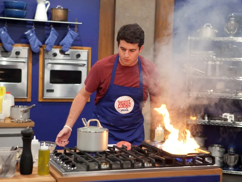 Alex Stein of the blue team starts a large grease fire while trying to work on his personal take on the hamburger during the Burger Challenge , as seen on Food Networks Worst Cooks in America, season 4.