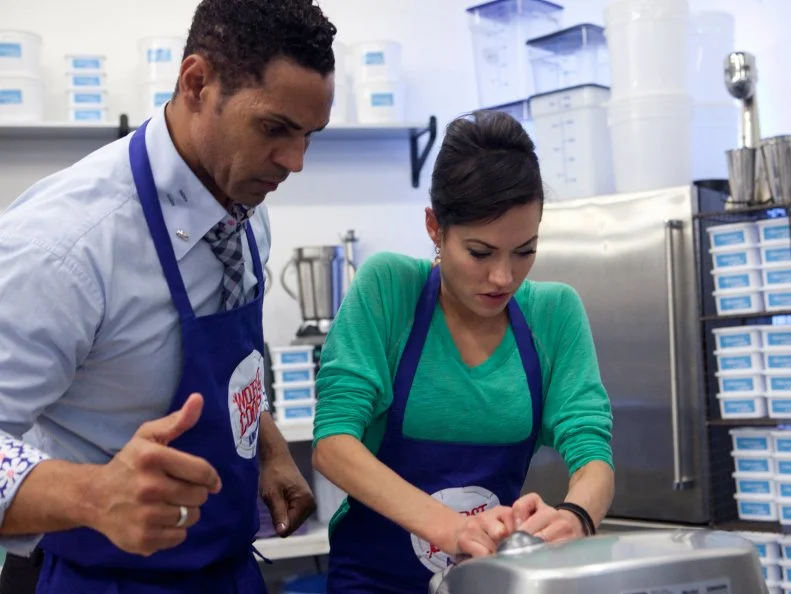 Carrie Lee Riggins of the blue team helps her teammate Chet Pourciau during the gelato and waffle cone challenge, as seen on Food Networks Worst Cooks in America, Season 4