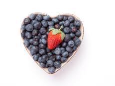 Blueberries and one Strawberry  in  a heart shaped bowl