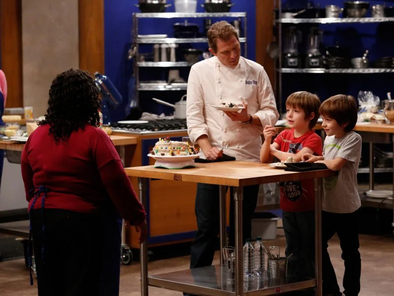 Chef Bobby Flay and Guest Judges Sawyer and Dash Dolgins taste the cake BlueTeam Recruit Carla Johnson prepared to celebrate their 7th Birthday in the Cake Bake off Challenge. While the cake doesn't look polished, Sawyer and Dash love the candy decorated cake. Recruits had to prepare their version of a Basic Vanilla Cake with Swiss Meringue Buttercream Frosting demonstrated by Chef Ron Ben-Israel. Chef Ron gave the recruits very specific directions to follow as a basis for their own unique cakes, as seen on Food Network's Worst Cooks in America, Season 4.