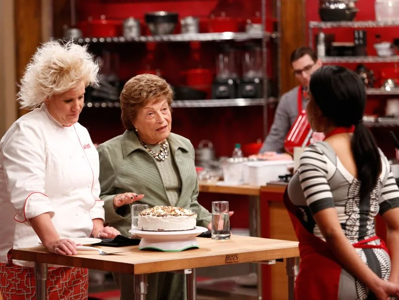 Red Team Leader Chef Anne Burrell and Guest Judge Rita Pasternack taste Red Team Recruit Rasheeda Brown's Pink Spice Crunch Cake.  All Red Team members had to prepare a cake to celebrate Rita's retirement in the Cake Bake Off Challenge in which recruits had to prepare a variation of a Basic Vanilla Cake with Swiss Meringue Buttercream Frosting demonstrated by Chef Ron Ben-Israel. Chef Ron gave the recruits very specific directions to follow as a basis for their own unique cakes. Rasheeda flavored her cake with Ginger, Vanilla and Butter Pecan nut mix, as seen on Food Network's Worst Cooks in America, Season 4.