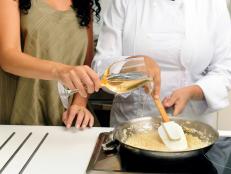 Cookery course: pouring wine into a pan with risotto