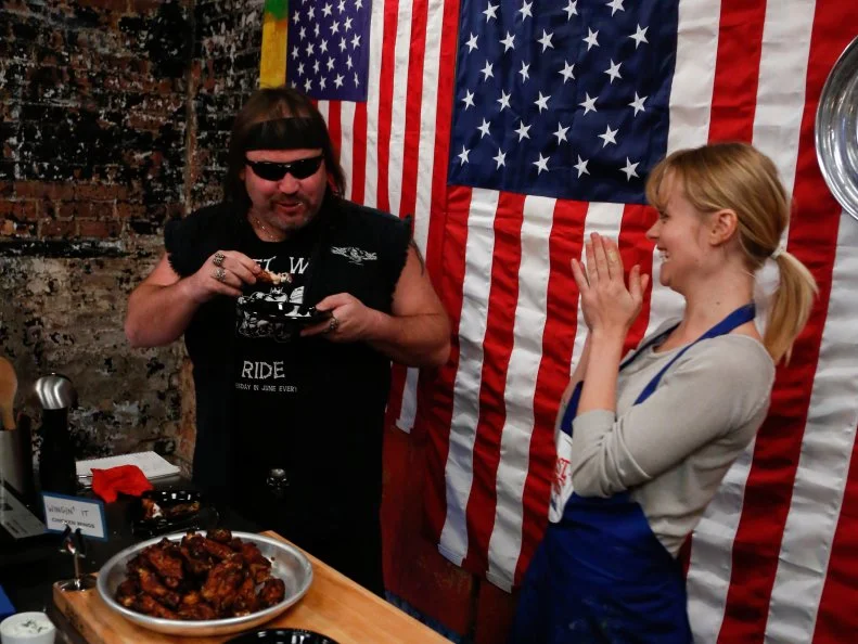 Blue Team Recruit Alina Bolshakova serves the appetizers she made for the "Biker Bites" challenge, and her appetizers seem to be a hit!  Alina made "Wingin' It Chicken Wings" and her assigned second appetizer: Grilled Sea Scallops on Tortilla Chips with Avocado Puree and Jalapeno Pesto. Alina made a spice rub for her chicken wings  flavored with sweet smoked pepper, cayenne pepper, onion and garlic powder, salt and pepper. She then made a glaze with beer, honey, marmalade, hot sauce, jalapeno, lemon juice, orange juice and white grape vinegar. Her dipping sauce was a greek yogurt sauce with cheese, scallions garlic, dill, salt and pepper. The recruits had to prepare their own chicken wing recipe after Chef Bobby Flay demonstrated how to make his Red Chile Chicken Wings with Chipotle Honey Glaze and an additional appetizer for hungry bikers- a tough crowd to please, as seen on Food Network's Worst Cooks in America, Season 4.
