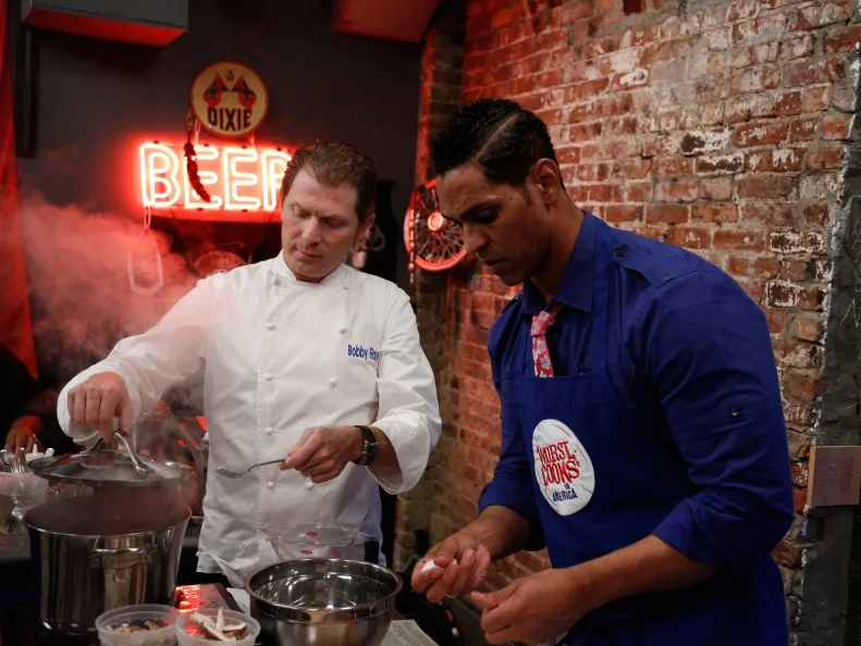 Blue Team Leader Chef Bobby Flay checks on the progress of Blue Team Recruit Chet Pourciau as he prepares appetizers for the "Biker Bites" challenge.  Chet is preparing Cajun Chicken wings spiced with Cajun seasoning, cayenne pepper, salt, pepper, and flour. His dipping sauce is mayonnaise, hot sauce, and green onions. His second appetizer is Grilled New Potatoes with Shitake Mushrooms, Shallots, and Goat Cheese. The recruits had to prepare their own chicken wing recipe after Chef Bobby Flay demonstrated how to make his Red Chile Chicken Wings with Chipotle Honey Glaze and an additional appetizer for hungry bikers- a tough crowd to please, as seen on Food Network's Worst Cooks in America, Season 4.