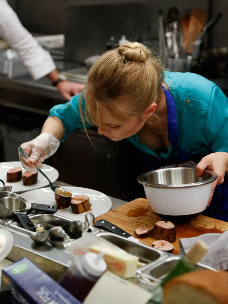 Blue Team Finalist Alina drizzles the pork medallions with pomegranate sauce as she plates her main dish. Blue Team Leader Chef Bobby Flay keeps a close eye on her and keeps her on track.  Chef Bobby is not allowed to touch the food.  He can give directions, but Alina must prepare this sophisticated meal on her own.  
Alina's Menu:
Appetizer -Lobster Scampi over Creamy Polenta with Garlic Chips
Main Dish -
Spice Rubbed Pork Tenderloin with Roasted Brussels Sprouts, Jalapeno Pesto and Pomegranates
Dessert -
Granny Smith Apples and Ginger Bread Pudding with Vanilla Bean Creme Anglaise
The recruits must prepare a three course restaurant-quality meal for a panel of distinguished culinary experts who will determine who takes home the $25,000 prize money, and the right to say they are no longer one of the worst cooks in America, as seen on Food Network's Worst Cooks in America, Season 4.