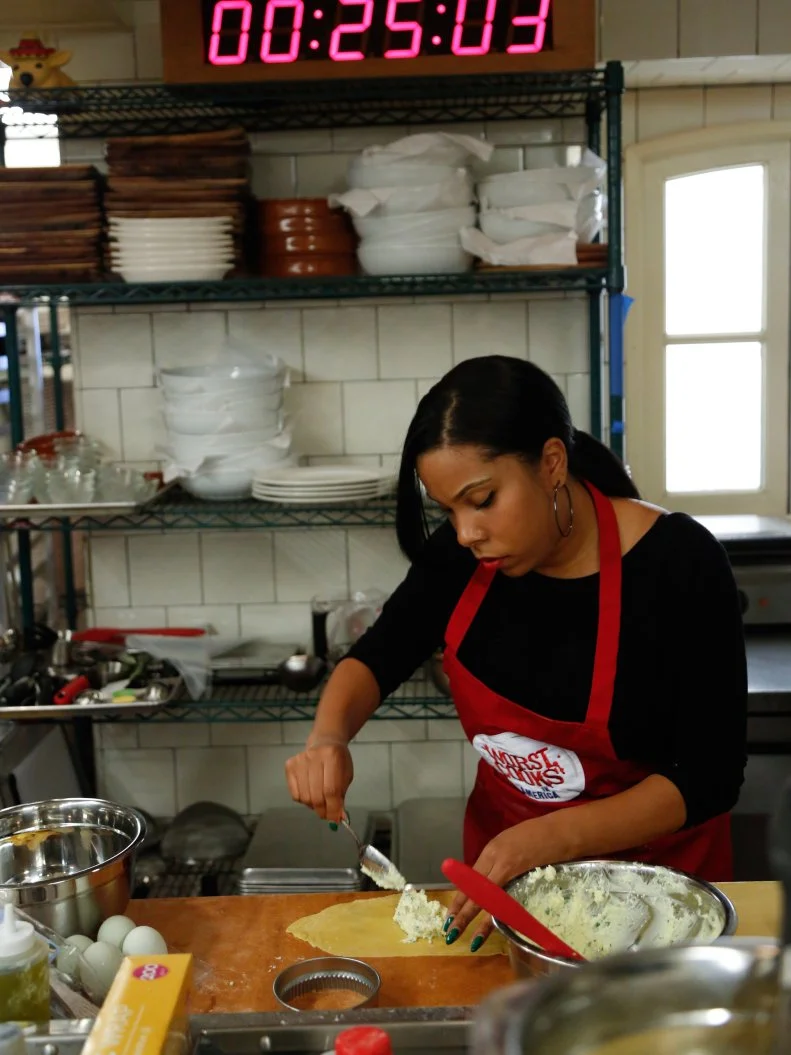 Red Team Finalist Rasheeda Brown putting the ricotta cheese and egg filling in her hand made pasta appetizer. Chef Anne keeps a close eye on her and keeps her on track.  Chef Anne is not allowed to touch the food.  She can give directions, but Rasheeda must prepare this sophisticated meal on her own.  It's a daring menu, but one Chef Anne is sure will insure a win for the Red Team.
Rasheeda's Menu:
Appetizer -
Raviolo al’Uovo
Main Dish -
Cornish Game Hen stuffed with Chicken Liver Pate
Frizzled Brussels Sprouts with Roasted Romanesco
Dessert -
Roasted Butternut Squash, Sauteed Apples and Toasted Walnut Crepes with Cinnamon Gelato

The recruits must prepare a three course restaurant-quality meal for a panel of distinguished culinary experts who will determine who takes home the $25,000 prize money, and the right to say they are no longer one of the worst cooks in America, as seen on Food Network's Worst Cooks in America, Season 4.