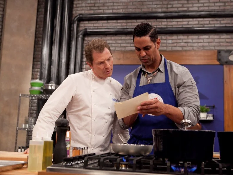 Chef Bobby Flay checks in with Chet Pouricau of the Blue Team while he works on his Fried Chicken with honey-pink peppercorn sauce and swiss Chard with serrano chili vinegar his dish will be served his mother Earlie Pourciau and Alina Bolshakova's friend Marshall Ferguson in a blind taste test, the will go on to represent Chef Flay and cook for a panel of culinary experts, as seen on Food Networks Worst Cooks In America, Season 4.