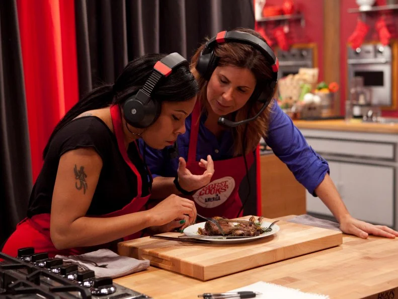 The red team (Sue Mangogna and Rasheeda Brown) speak to Chef Anne Burrell) via headset while they try and describe an unfamiliar dish to the chef that she must replicate by their description alone, as seen on Food Networks Worst Cooks In America, Season 4.