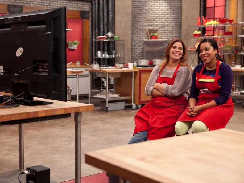 Rasheeda Brown and Sue Mangogna of the red team, watch on monitors while Rasheeda's broccoli rabe ravioli with parmigiano and pistachios is served to her twin sister Aisha as well as her teammates son Christopher Mangogna, the entree's will be judged by the loved ones in a blind taste to decide who will represent Chef Anne Burrell in front of a panel of culinary experts, as seen on Food Networks Worst Cooks In America, Season 4.