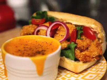 Host Jeff Mauro whisks grits for his cheesy grits side dish he's making at home, as seen on Food Network's Sandwich King.