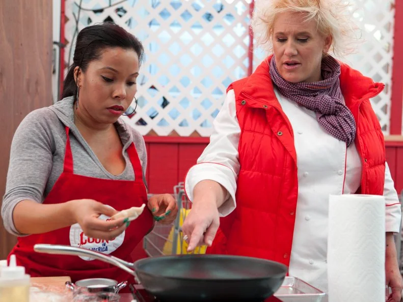 Chef Anne Burrell checks in on Rasheeda Brown of the Red team as she folds and cooks her dumplings, each team member is responsible for making and cooking 20 dumplings each, the dumplings were served to customers inside Stew Leonards, the customers will vote to select the winning team, as seen on Food Networks Worst Cooks in America, season 4.