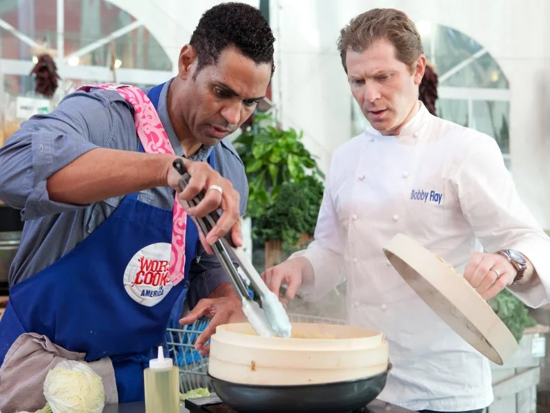 Chef Bobby Flay checks in with Chet Pouricau of the Blue team as he folds and cooks his dumplings, each team member is responsible for making and cooking 20 dumplings each, the dumplings were served to customers inside Stew Leonards, the customers will vote to select the winning team, as seen on Food Networks Worst Cooks in America, season 4.