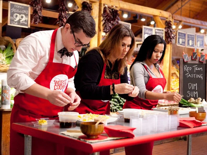At the Red Team tasting table customers line up and are served dumplngs, each team member was responsible for making and cooking 20 dumplings each, the customers will vote to select the winning team, as seen on Food Networks Worst Cooks in America, season 4.