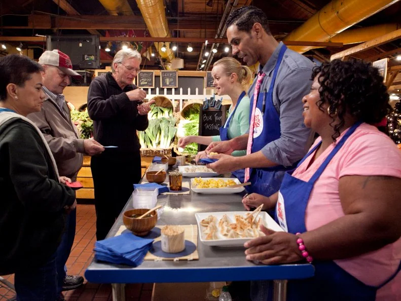 At the Blue Team tasting table customers line up and are served dumplngs, each team member was responsible for making and cooking 20 dumplings each, the customers will vote to select the winning team, as seen on Food Networks Worst Cooks in America, season 4.