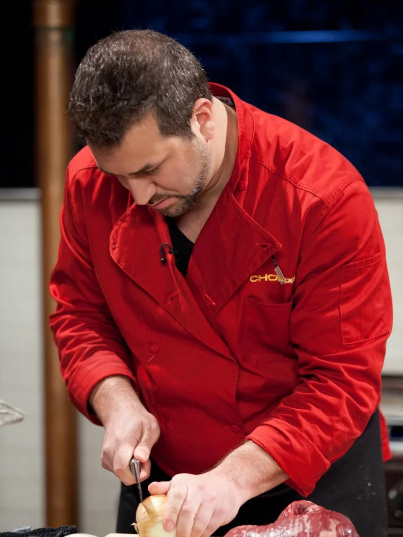 Singer Joey Fatone slices an onion, as seen on Food Network’s Chopped All Stars, Season 14.
