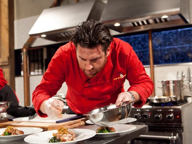 All-Star Chef Scott Conant working on his entree which must include: suckling goat, broccoli rabe, farro and cheddar filled pretzels ,as seen on Food Network's Chopped All-Stars, Season 14.