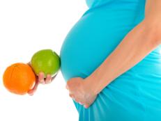 Pregnant woman's belly, apple and orange