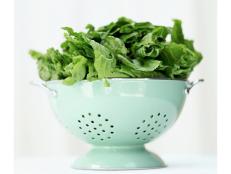 a metal colander with green leaves