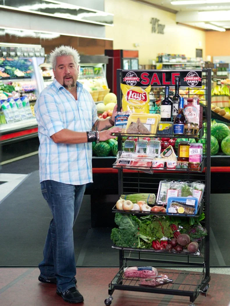 Host Guy Fieri with Guy's Sale Cart during the cooking part of Game 1, Frozen Food Feud, Five Star Dinner, 30 min cooking time, as seen on Food Network's Guy's Grocery Games, Season 1.