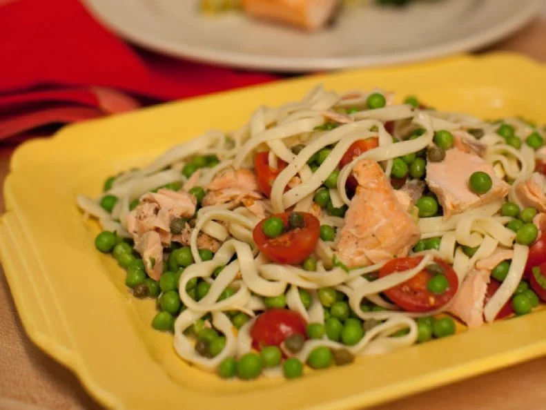 The dish recipe: Salmon filet seasoned with coriander, Italian seasoning, and lemon and steamed in a foil packet. The cooked salmon is flaked and tossed with fresh linguini, cherry tomatoes, peas, and capers and tossed in a Dijon vinaigrette. Salmon and Veggie Linguini "Sal Monguini"  as seen of Food Network's The Kitchen, Season 1.