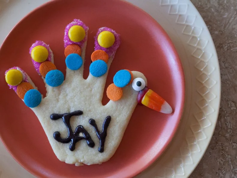 Hand cookie place cards decorated with sprinkles and candy, by Kids for Thanksgiving.