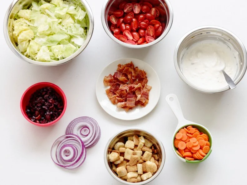 LAYERED BLUE CHEESE AND BACON WEDGE SALADFood Network KitchenRed Onion, Bacon, Blue Cheese, Sour Cream, Mayonnaise, Worcestershire Sauce, IcebergLettuce, Grape Tomatoes, Kalmata Olives, Carrots, Croutons