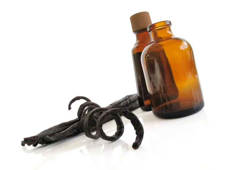 Sun-dried vanilla pods with bottles of vanilla essence
