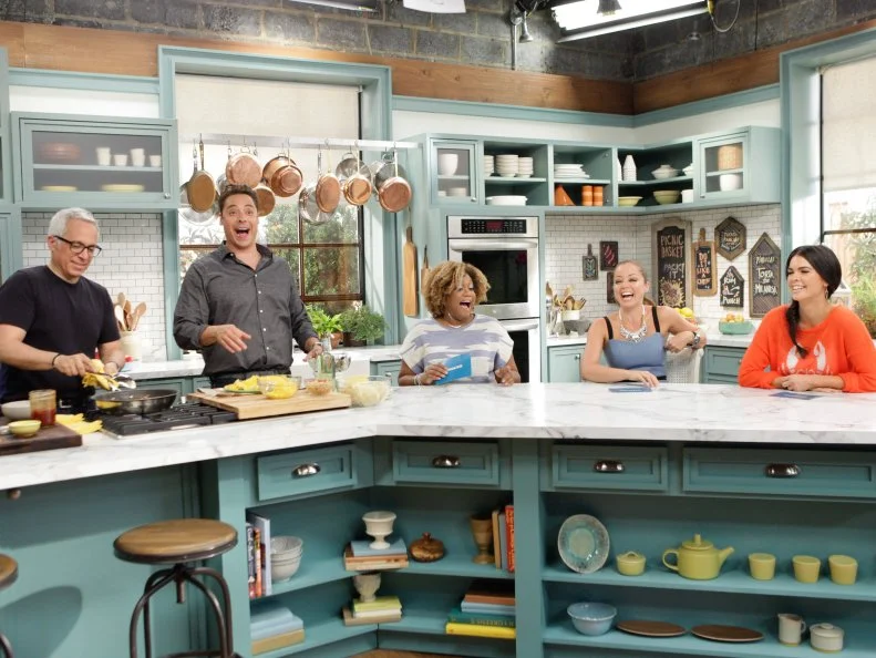 Geoffrey Zakarian, left, Jeff Mauro, second from left, Sunny Anderson, seated left, Marcela Valladolid, seated middle, and Katie Lee, seated right, share a laugh, as seen on Food Network's The Kitchen, Season 2.
