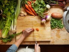High angle shot of a woman cutting up vegetables on a cutting board