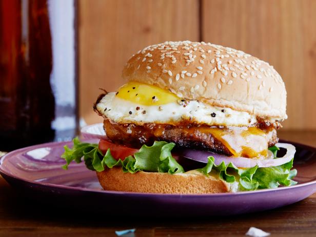 FNK HANGOVER BREAKFAST SAUSAGEANDEGG BURGER Food Network Kitchen Food Network Mayonnaise, Sriracha, Maple Syrup, Hamburger Bun, Lettuce, Tomato, Breakfast Sausage, Red Onion, Cheddar Cheese, Egg