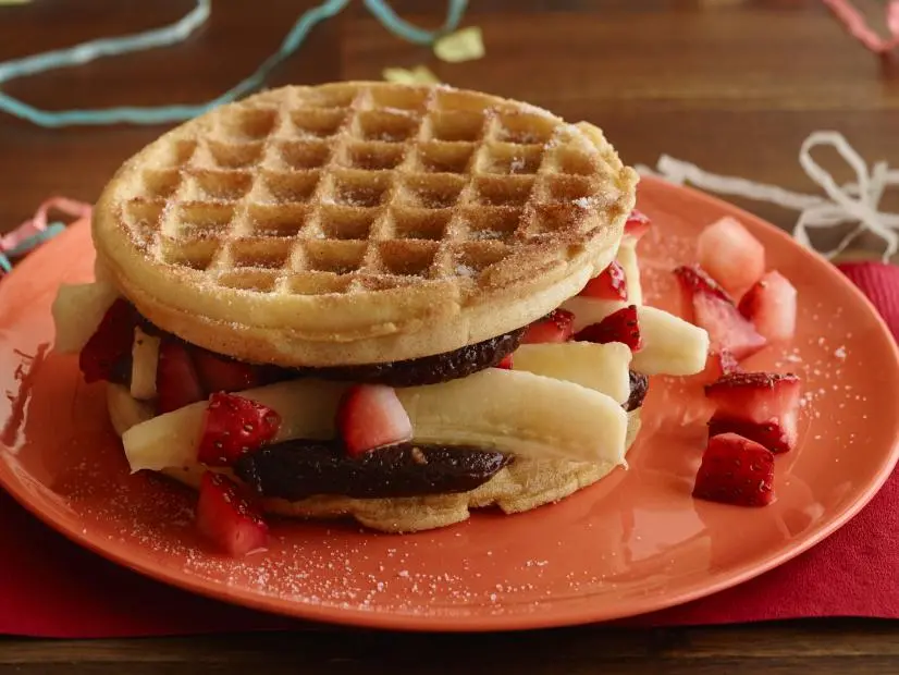 FNK HANGOVER BERRY, BANANA, CHOCOLATEHAZELNUT WAFFLE SANDWICH Food Network Kitchen Food Network Sugar, Cinnamon, ChocolateHazelnut Spread, Whipped Cream Cheese, Waffles, Unsalted Butter, Strawberries, Banana