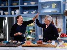 Co-host Jeff Mauro, left, demonstrates his Bananas Foster Banana Bread for fellow host Geoffrey Zakarian as seen on Food Network's The Kitchen, Season 7.