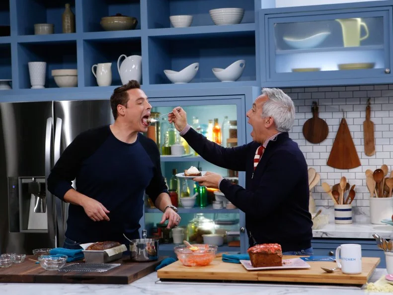 Co-host Jeff Mauro, left, demonstrates his Bananas Foster Banana Bread for fellow host Geoffrey Zakarian as seen on Food Network's The Kitchen, Season 7.