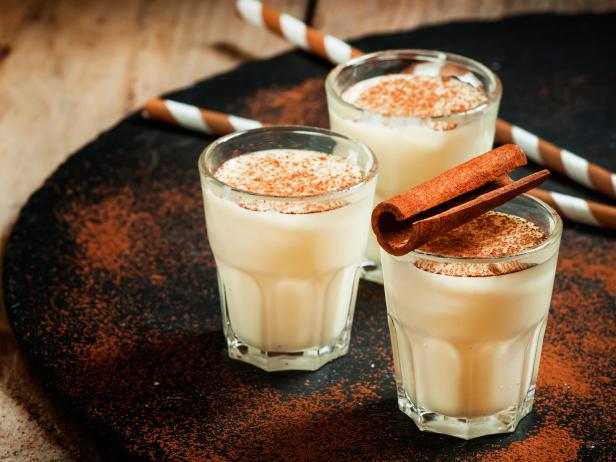 Traditional winter eggnog  with milk, rum and cinnamon, sprinkle with grated nutmeg, selective focus
