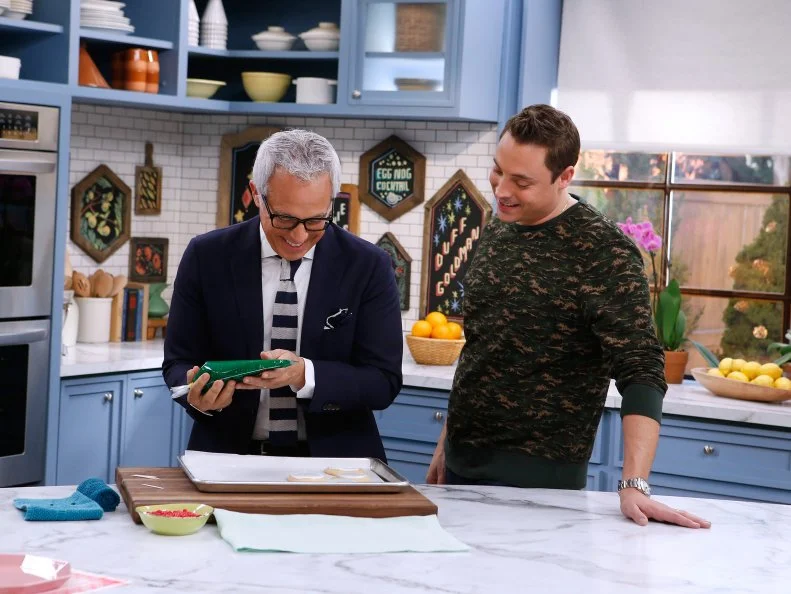 Host Geoffrey Zakarian, left, demonstrates his Christmas Wreath Icing technique for fellow host Jeff Mauro as seen on Food Network's The Kitchen, Season 8.