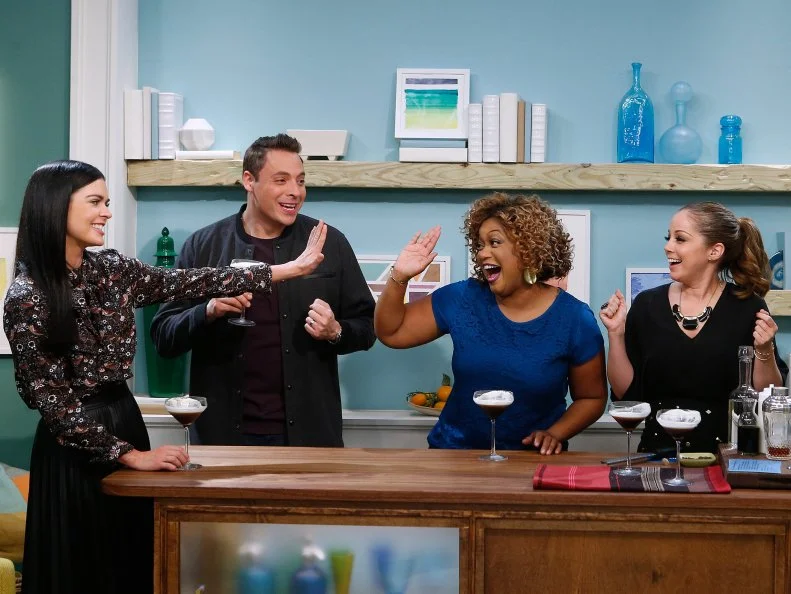 From left, hosts Katie Lee, Jeff Mauro, Sunny Anderson and Marcela Valladolid sample a Black Russian Munich Style cocktail made by fellow host Geoffrey Zakarian as seen on Food Network's The Kitchen, Season 8.