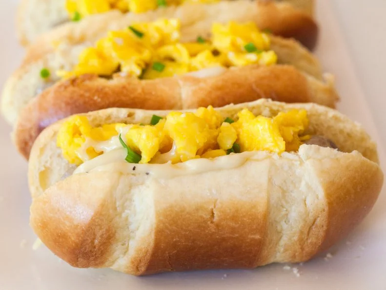 Mini French Brioche rolls split and filled with breakfast sausge, sausage gravy, eggs and chives, Surprise your family with hot dogs for breakfast. Recipe and photo by Jackie Alpers for Food Network.com